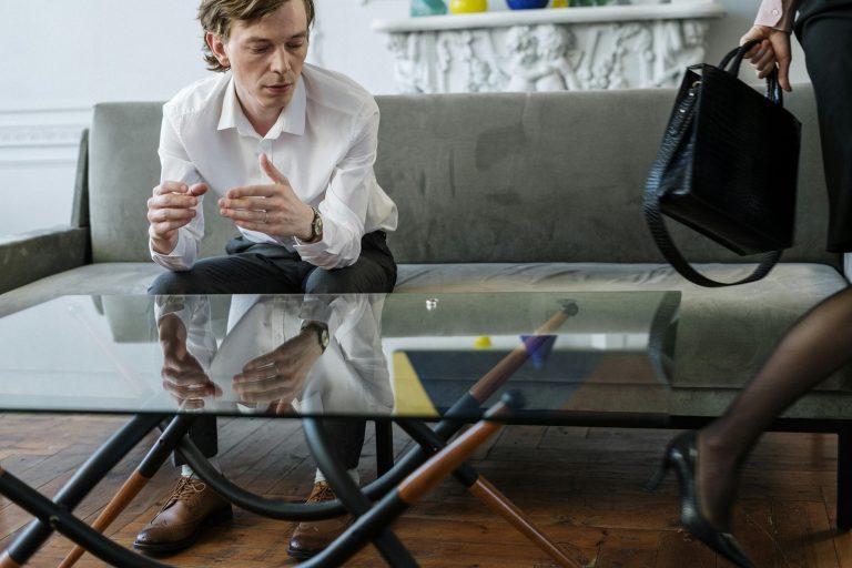Man op een bank vrouw loopt weg laat ring op tafel als afbeelding bij een blog over Pensioenkennis bij scheiding